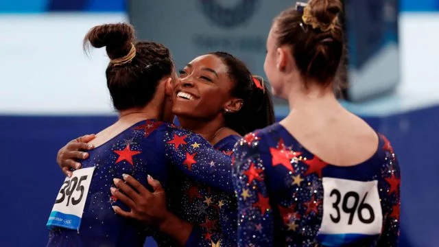 Simone Biles abrazando a compañeras de su equipo tras ganar el oro en los Juegos Olímpicos de París 2024.